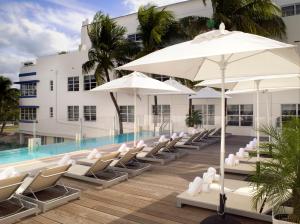 迈阿密海滩南海滩布里克沃特酒店的一座带椅子和遮阳伞的游泳池位于一座建筑旁边