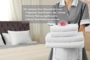 阿罗萨阿罗萨库尔姆阿尔平Spa酒店的一位女士在旅馆房间拿着一堆毛巾