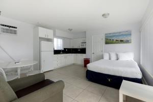 好莱坞Hollywood Broadwalk Oceanside Hotel的一间白色卧室,配有床和厨房