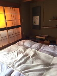 ShishikuiGuest House Mitsuka的一张带镜子的客房内的一张未铺好的床