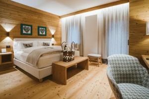 圣维托-迪卡多雷FIORI Dolomites Experience Hotel的配有一张床和一把椅子的酒店客房
