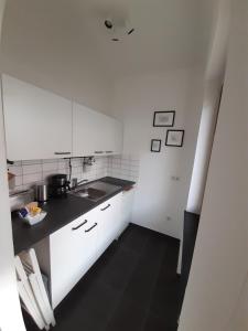 卡塞尔Apartment in zentraler Lage Kassels的厨房配有白色橱柜和黑色地板