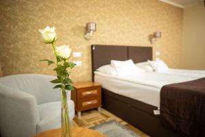 塞格德多姆酒店的一间卧室配有一张床和一个玫瑰花花瓶