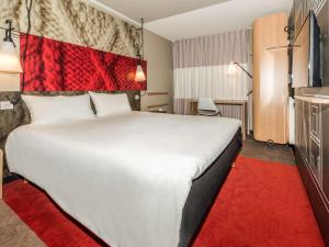 楠泰尔楠泰尔拉德芳斯宜必思酒店的酒店客房设有一张白色大床,铺有红色地毯