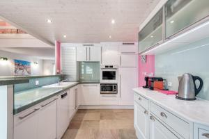 拉弗洛特Maison Amande的厨房配有白色橱柜和粉红色的墙壁