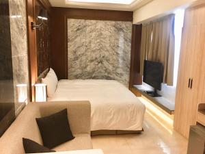 台中市枫华沐月台湾大道行馆的一间卧室配有一张床、一张沙发和一台电视。