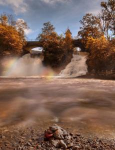 斯塔沃洛Villa du Lac de Coo的一条有瀑布的河流和一座有彩虹的桥梁