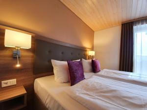 韦特海姆尹登赫恩维森酒店的酒店客房配有一张带紫色枕头的大床