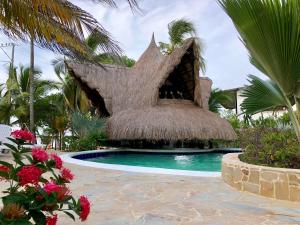 科韦尼亚斯Cabañas Aqua Blue的一个带茅草屋顶游泳池的度假酒店