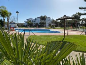 科斯塔巴伦娜Apartamento en Bahia Golf - Costa Ballena的公园内带遮阳伞的游泳池