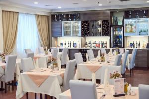 乌拉尔斯克普希金酒店的用餐室配有白色的桌子和白色的椅子