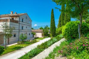 锡罗洛Il Casale Di Giulia的一座花园,位于一座种有树木和鲜花的建筑前