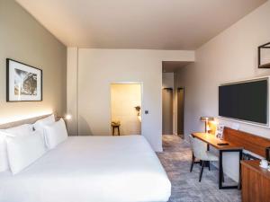 雷恩布列塔尼雷恩中心广场美居酒店的酒店客房设有一张床、一张书桌和一台电视机。