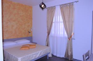 兰佩杜萨La Fenice的一间卧室配有带橙色枕头的床和窗户。