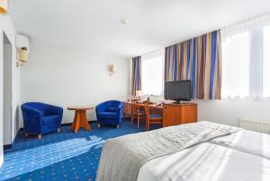 莱格尼察Qubus酒店的酒店客房,配有一张床、一张桌子和椅子