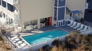 杜威海滩Atlantic View Hotel的享有带游泳池和椅子的建筑的正面景色