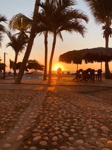 巴拉奥纳省圣克鲁斯Hotel Al Mare的棕榈树海滩,坐在长凳上的人