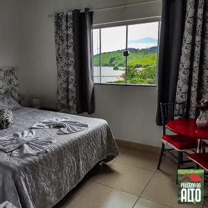 卡皮托利乌Pousada Do Alto的一间卧室设有一张床和一个大窗户