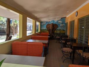 LibweziKambua Resort的一间设有桌椅的餐厅,并装饰有大象壁画