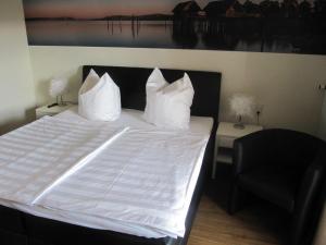农嫩霍恩Pension Sonnengrund的一张带白色床单和黑椅的床