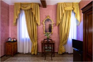 威尼斯马可尼酒店的一间设有黄色窗帘、桌子和镜子的客房