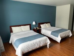 MetabetchouanMotel Le Rond Point的配有蓝色墙壁和木地板的客房中的两张床