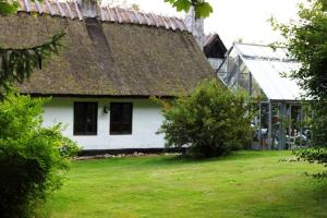 弗雷登斯堡Stråtækt idyl i skoven的茅草屋顶和院子的老房子