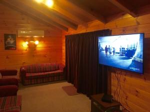 奥阿库尼Alpine Cabin - Ohakune Holiday Home的小屋内的客厅配有大屏幕平板电视