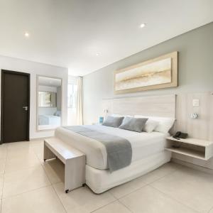 亚松森丹尼里亚松森酒店 的白色卧室设有一张大床和镜子
