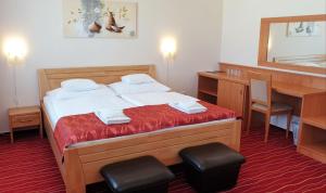布达佩斯黛安娜俱乐部酒店的一间卧室配有一张带书桌和镜子的床