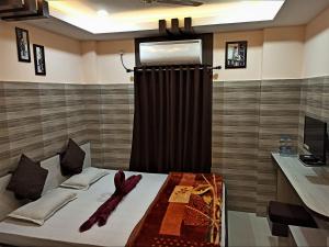 古瓦哈提Hotel Prince B的一间卧室配有一张带窗帘的床和电视
