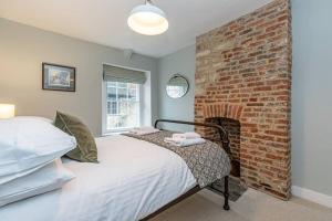 伍德斯托克Oxfordshire Living - The Bowler Hat Cottage - Woodstock的一间卧室设有砖墙和一张床