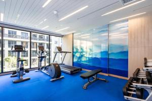 华欣Maven Stylish Hotel Hua Hin的一间设有蓝色地板和大窗户的健身房