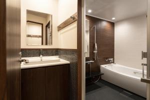 札幌Miidokoro House Hotel的浴室配有盥洗盆、浴缸和浴缸。