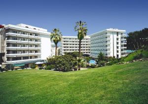 罗列特海岸Hotel Gran Garbi & AquaSplash的一座棕榈树公园,位于一座建筑前