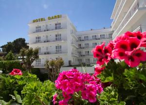 罗列特海岸加尔比别墅酒店的前面有粉红色花的建筑