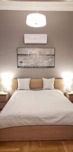 布达佩斯至尊城市中心公寓的一间卧室配有一张带两盏灯的大型白色床。