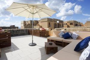 MġarrGetawayNpetto Private Duplex Maisonette with Jacuzzi Hot Tub的屋顶上设有一个带沙发和遮阳伞的庭院