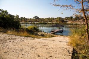 龙杜Hakusembe River Campsite的一条在泥土路旁的河上的小船