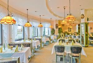 古本Landgasthof & Hotel Waldow的餐厅设有白色的桌椅和窗户。