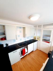 雷利Rayleigh Town Centre 2 Bedroom Apartment的厨房配有白色橱柜和黑色台面