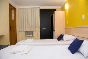 里约热内卢Hotel Villa Rica的黄色墙壁的客房内设有两张白色的床
