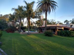 玛利亚镇La Isolina Club de Campo的庭院前有棕榈树的房子
