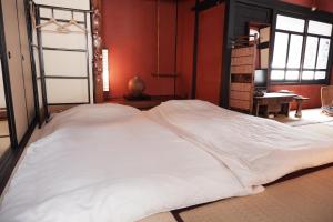 广岛一棟貸ゲストハウス 傾㐂屋 Kabukiya的红色墙壁的房间里一张大白色的床