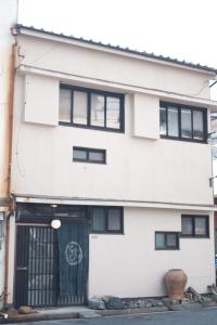 广岛一棟貸ゲストハウス 傾㐂屋 Kabukiya的白色的建筑,设有黑窗和门