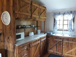 路易特里哈特Declan House的厨房配有木制橱柜和墙上的时钟