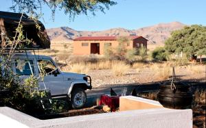 索利泰尔Namib Desert Campsite的停在田野房屋旁边的卡车