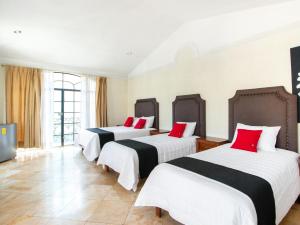 圣路易斯波托西Capital O San Jose, San Luis Potosi的酒店客房,配有3张带红色枕头的床