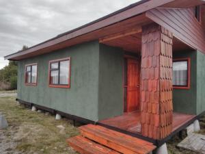 AlerceCabañas Troncos de Alerce en Puerto Montt con tinaja caliente的绿色的小房子,设有木门廊