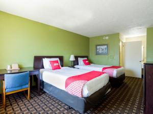 彭萨科拉OYO Hotel Pensacola I-10 & Hwy 29的绿墙和书桌的客房内的两张床